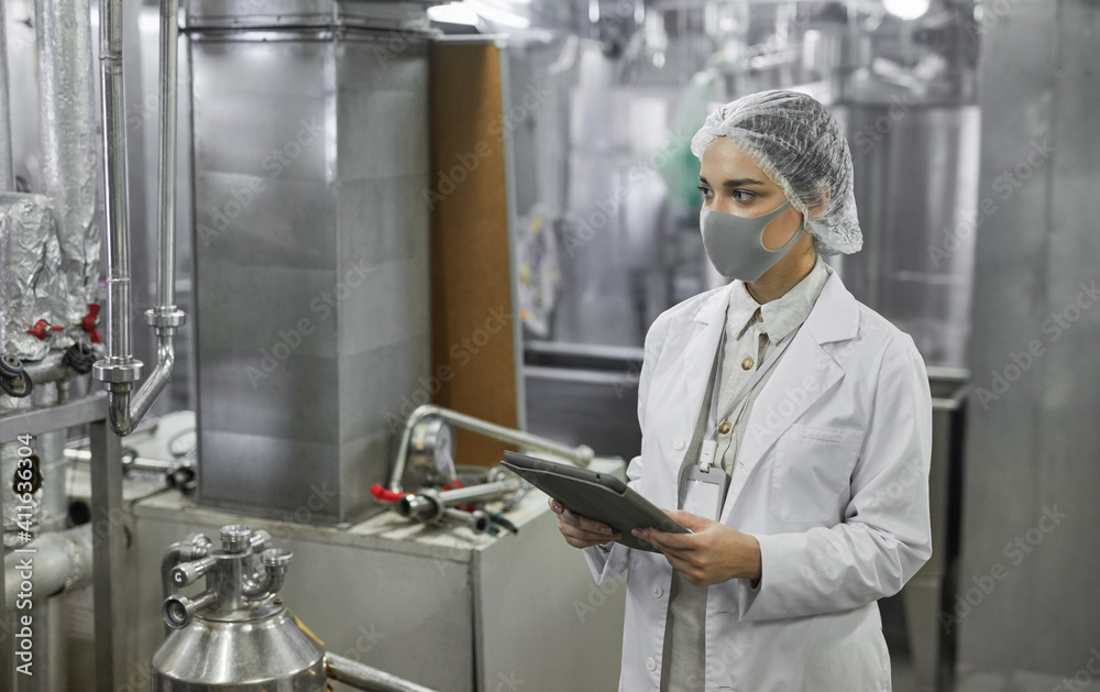 Φωτογραφία Waist up portrait of female worker wearing mask and holding digital tablet durin