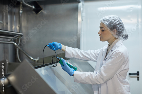 Konstfotografi Side view portrait of young female worker holding temperature meter while probin