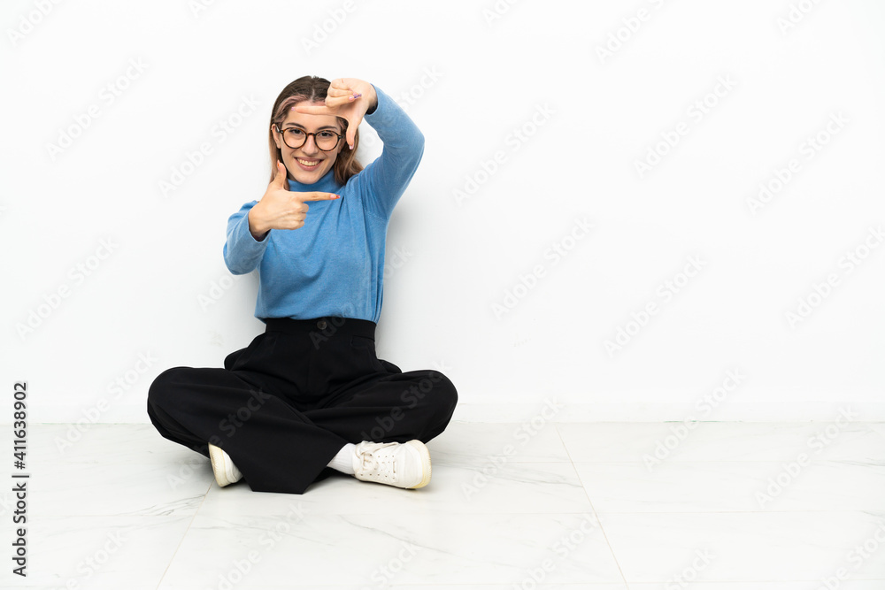 Young Caucasian woman sitting on the floor focusing face. Framing symbol Young Caucasian woman sitting on the floor focusing face. Framing symbol
