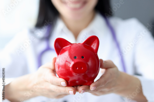 Doctor holds piggy bank in his hands
