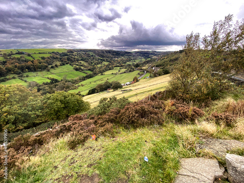 Autumn landscape, looking up, Shibden Valley, with gorse bushes, extensive meadows, fields, distant hills, and cloudy skies near, Halifax, Yorkshire, UK 