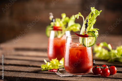Bloody or virgin mary cocktail served in a cup with celery sticks and cherry tomatoes photo