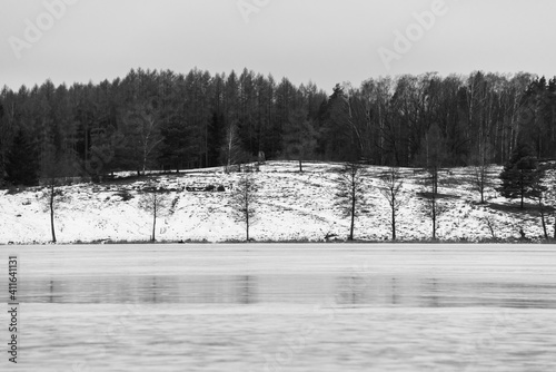 Fototapeta Naklejka Na Ścianę i Meble -  Typical Polish winter landscape in black and white. Frozen lake and forest. Selective focus. Rzeck village, Masuria, Poland. 