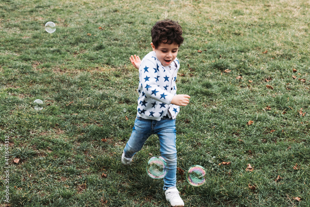 Little boy running with soap bubbles around him Little boy running with soap bubbles around him