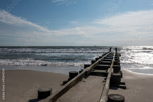 Coastal landscape showing the sandy beach  rough ocean and wooden jetty extending into the ocean