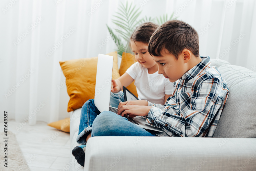 Child blogging in internet, concentrated boy and girl with laptop at home. two children boy and girl use laptop Child blogging in internet, concentrated boy and girl with laptop at home. two children boy and girl use laptop