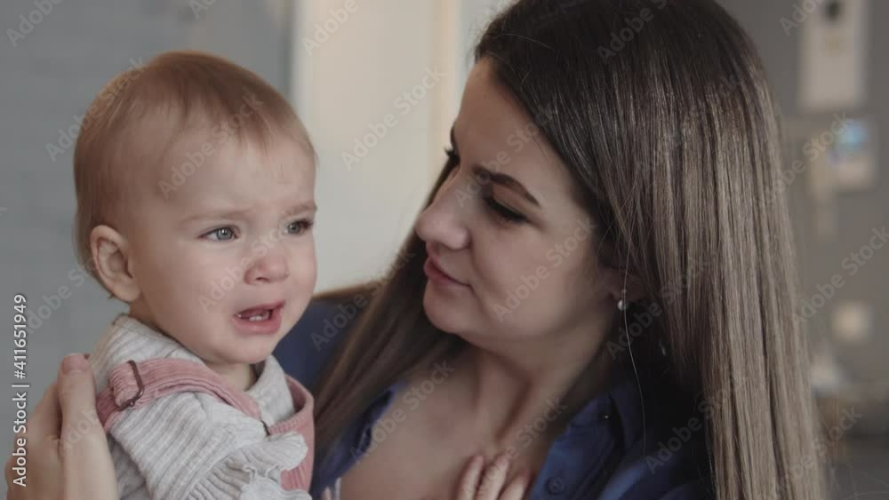 Upset naughty little girl crying sitting on mothers hands, scared or hungry Upset naughty little girl crying sitting on mothers hands, scared or hungry