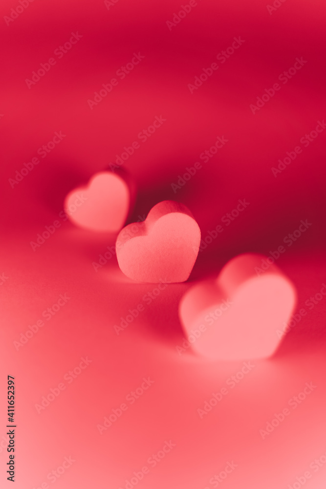 Three little pink hearts of sponge situated together on a pink background with a red lighting. San Valentine's day backgrounds concept