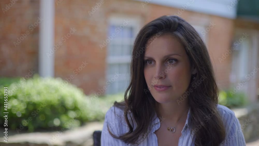 Close Up of a Beautiful Caucasian Brunette Young Woman Sitting Outdoors Talking Close Up of a Beautiful Caucasian Brunette Young Woman Sitting Outdoors Talking