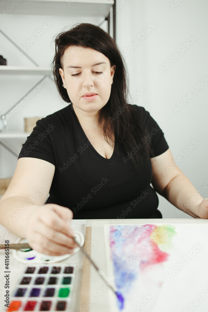 Young concentrated woman do watercolor drawing