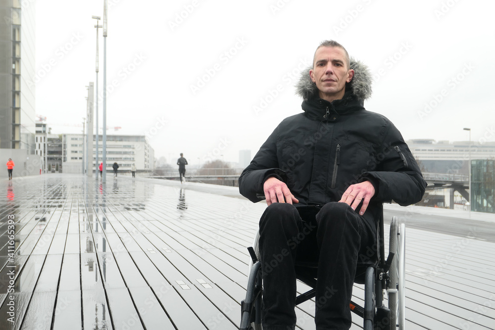 Concept of disabled person. Man in a wheelchair looking the camera, outside in the street. Concept of disabled person. Man in a wheelchair looking the camera, outside in the street.