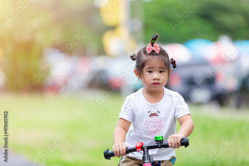 Little asian girl play balance bike at park. Happy little children play at park.