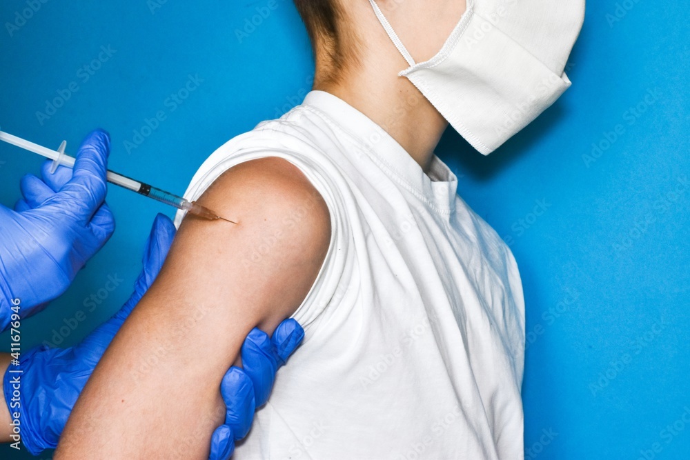 The doctor makes a vaccination of a child in a medical mask, close-up. Vaccination concept. The doctor makes a vaccination of a child in a medical mask, close-up. Vaccination concept.