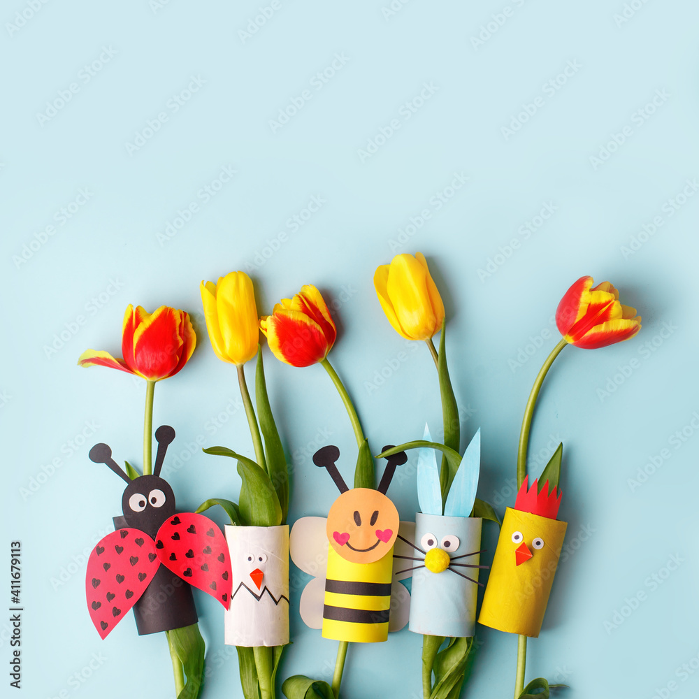 Happy easter spring toy collection and fresh flowers on blue background, kids holiday party concept background. Paper crafts, DIY. creative idea from toilet roll. reuse, recycle - obrazy, fototapety, plakaty 