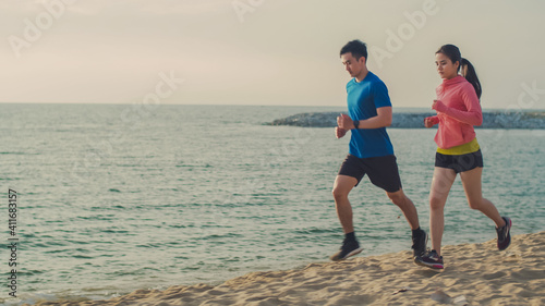 Active couple jogging outdoors during sunrise at the seaside, Asian couple running in nature living healthy lifestyle concept.