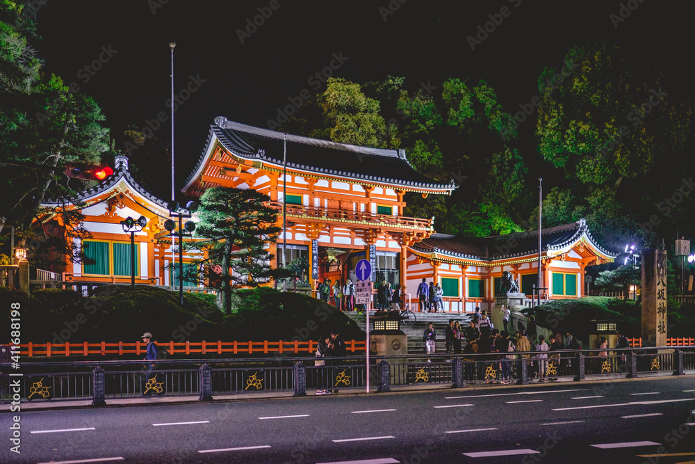 The great gate and entrance building of the Yasaka shrine with visitors in night, Kyoto, Japan