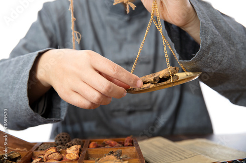 A doctor of traditional Chinese medicine weighing herbs photo