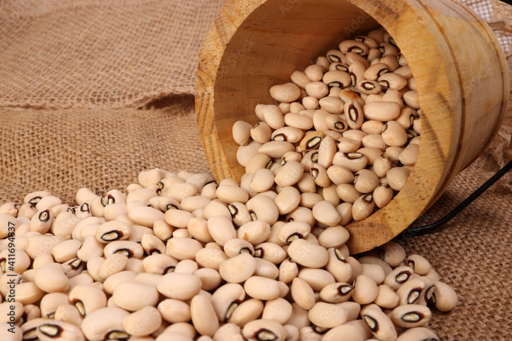 Blackeye beans in wooden small bucket on jute yarn fabric background Blackeye beans in wooden small bucket on jute yarn fabric background