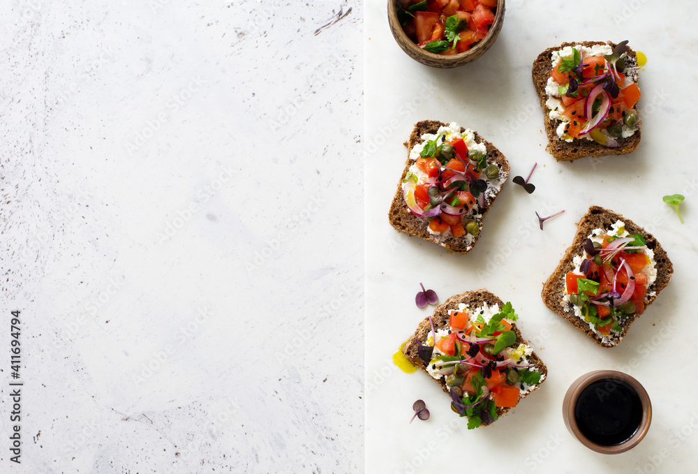 Open face rye bread sandwiches with soft cheese, tomatoes, red onions and capers