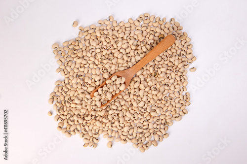 Blackeye beans in wooden scoop spoon top view on white background