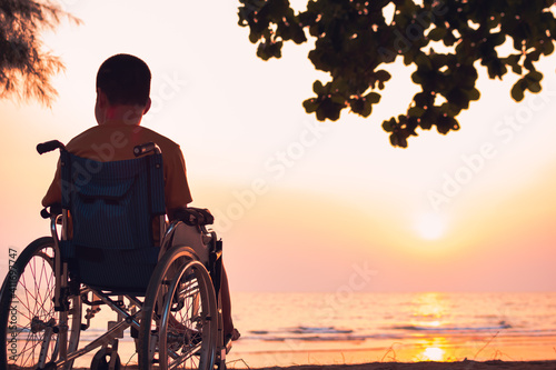 Asian special child on wheelchair on the sea beach with sunset on travel time in holiday family and learning about nature around the sea,Lifestyle in the education age kids,Happy disabled kid concept.