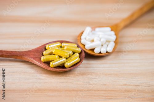 Turmaric powder capsules and probiotic capsules in wooden spoon, suppliment capsules, herbal powder