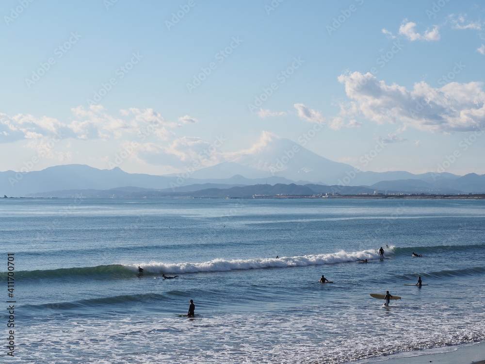 Obraz premium 富士山の見える雄大な景色の前で波を待っているサーファー