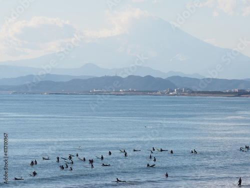 富士山の見える雄大な景色の前で波を待っているサーファー