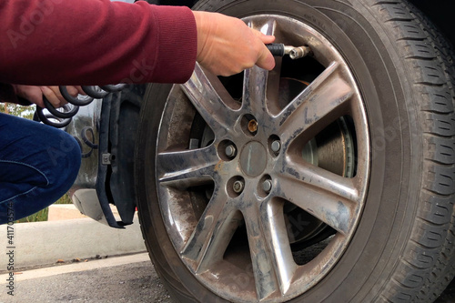 Close up of an older woman, female hands using automated air pump to inflate car tire with low pressure.