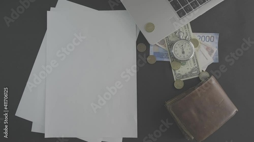 A white piece of paper with money, laptop and a stopwatch