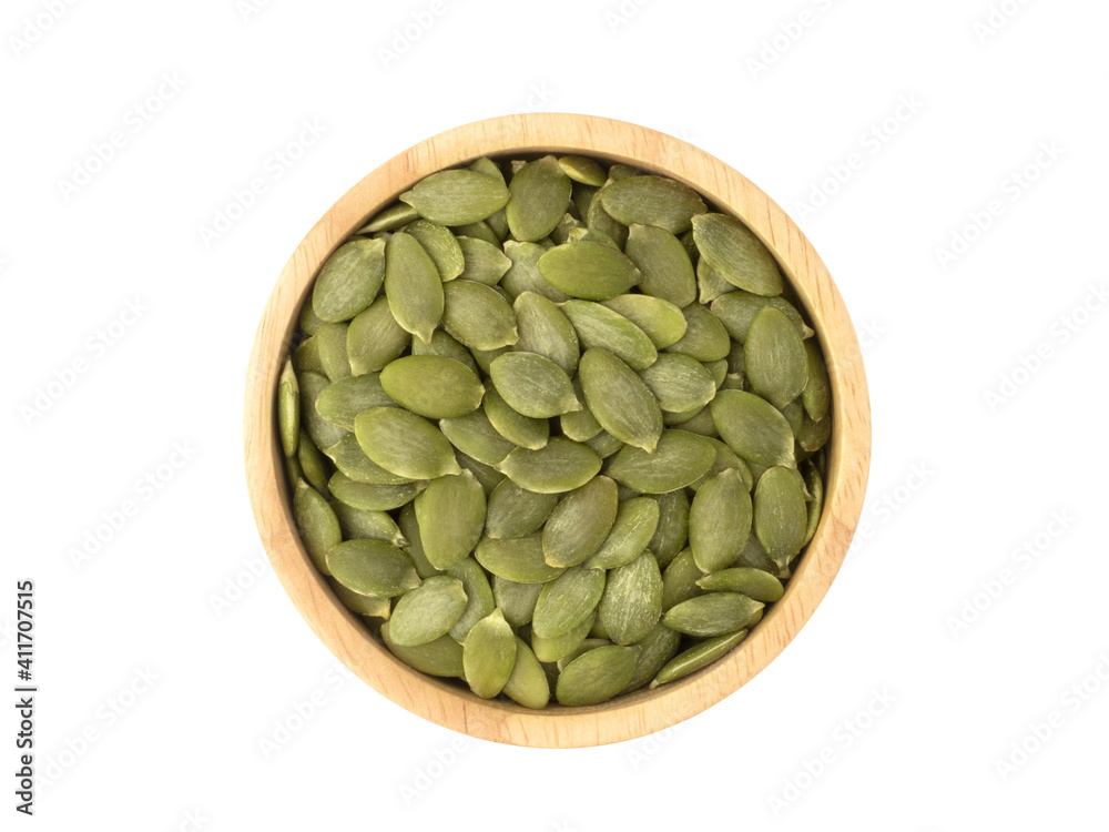 Fototapeta premium Organic pumpkin seeds in circle shaped wooden bowl top view isolated on white background. Organic pumpkin seeds healthy ingredients food concept.