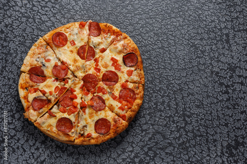 Pepperoni pizza, on a black textured background. Italian food concept. Close-up.