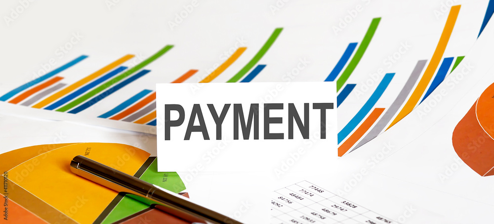 PAYMENT text on paper on chart background with pen PAYMENT text on paper on chart background with pen