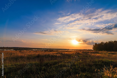 summer landscape with meadow and beautiful sunset with forest and river