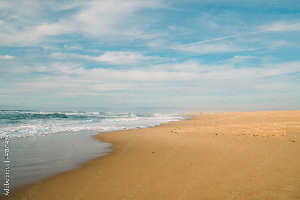 Wide sandy beach, blue sea, and beautiful cloudy sky.
