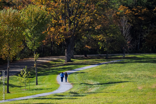 People walking along path on a sunny morning in october under autumn light. Burlington, Vermont
