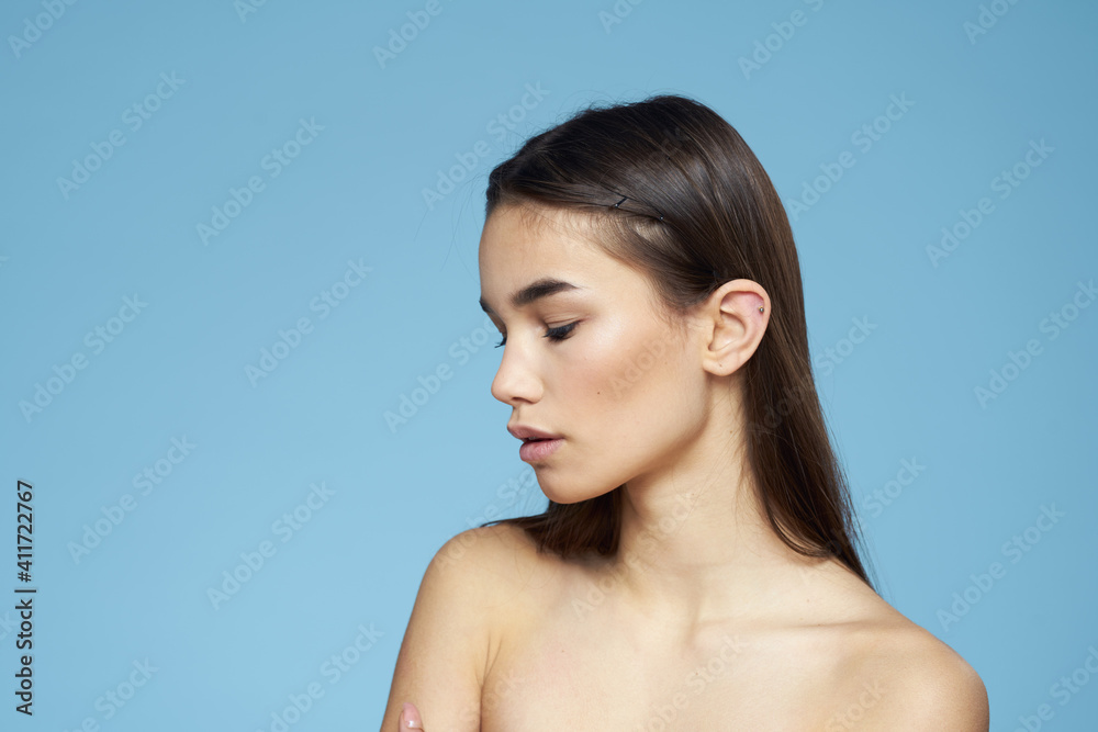 brunette with bare shoulders cosmetics close-up skin care blue background