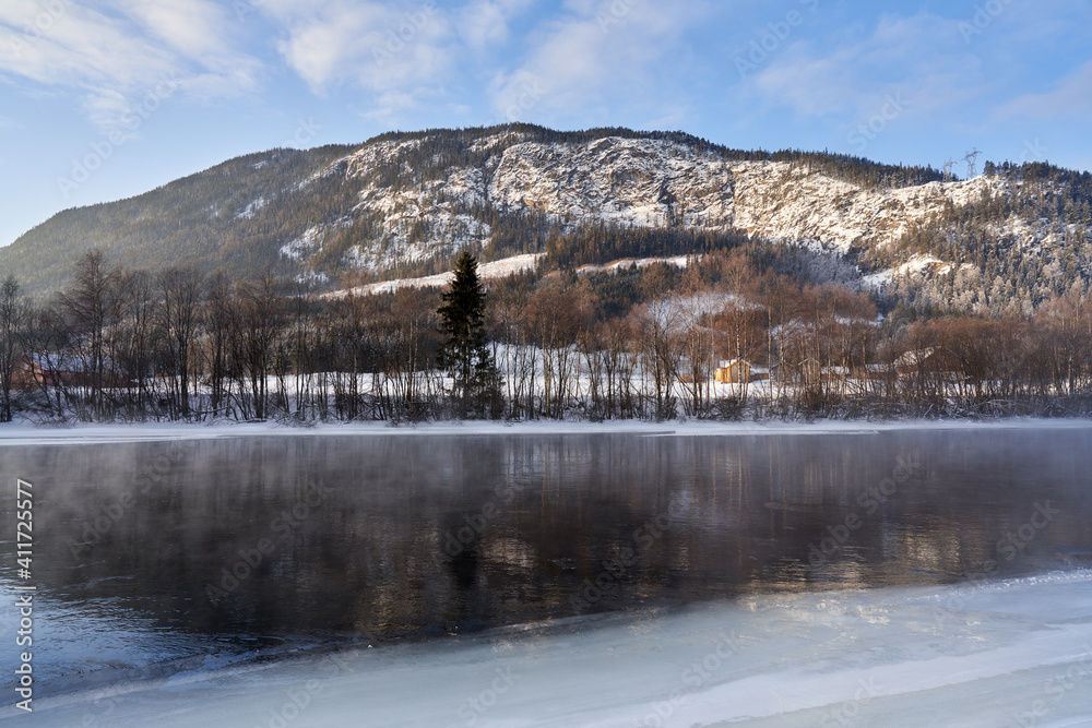 The river is about to freeze. It is very cold and the river is much warmer than the air, therefore the smoke or the damp from the river. Shot at Gol, Norway in February. Minus 20 degreases Celsius. The river is about to freeze. It is very cold and the river is much warmer than the air, therefore the smoke or the damp from the river. Shot at Gol, Norway in February. Minus 20 degreases Celsius.