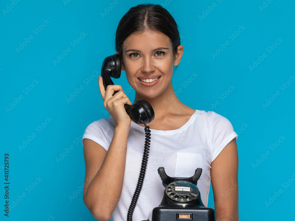 casual woman talking on an old telephone and smiling casual woman talking on an old telephone and smiling