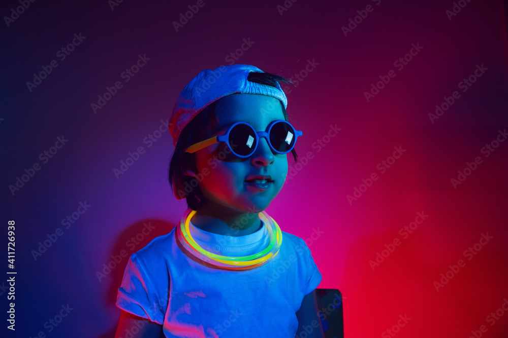 cyberpunk boy child in a white T shirt and large headphones listening to music on the background of the wall