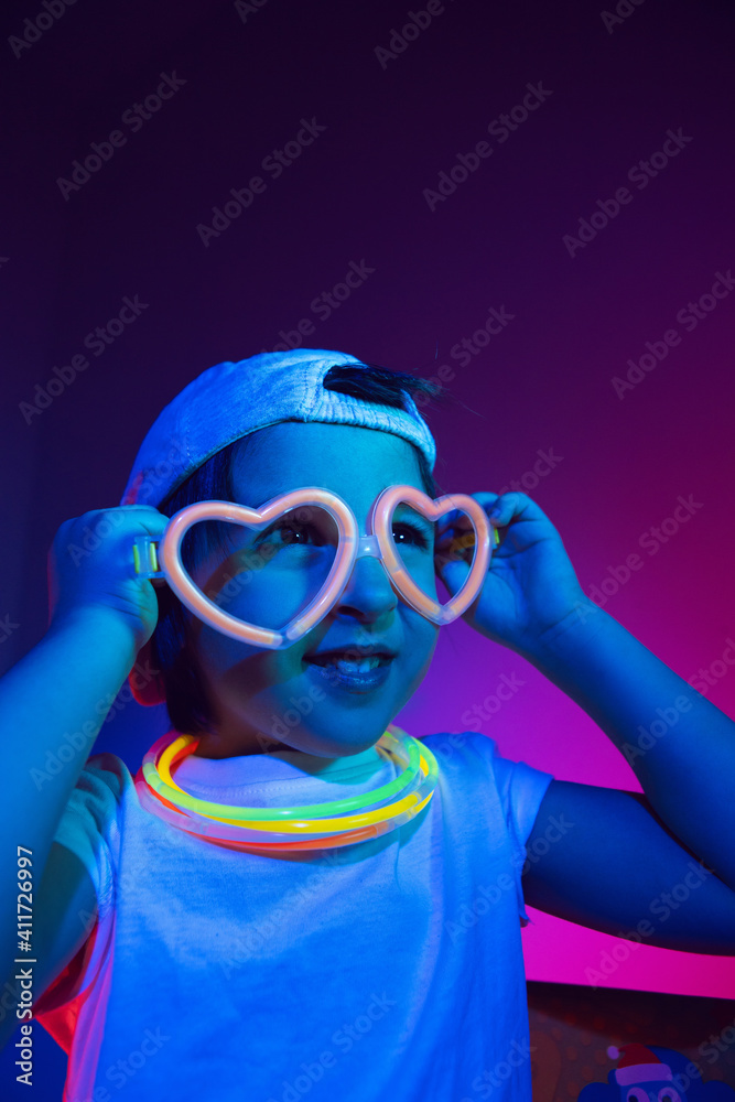 cyberpunk boy child in a white T shirt and large headphones listening to music on the background of the wall
