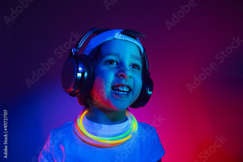cyberpunk boy child in a white T shirt and large headphones listening to music on the background of the wall
