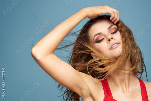 Pretty woman bright makeup wavy hair close-up model blue background