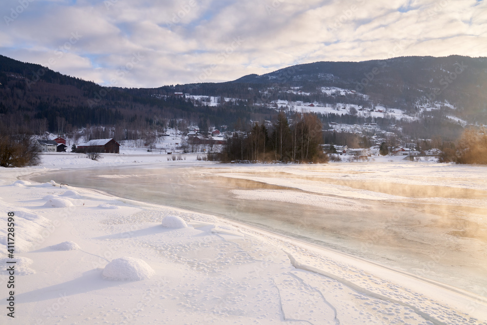 The river is about to freeze. It is very cold and the river is much warmer than the air, therefore the smoke or the damp from the river. Shot at Gol, Norway in February. Minus 20 degreases Celsius. 