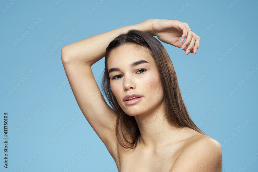 Woman with naked shoulders long hair cosmetics attractive look blue background Woman with naked shoulders long hair cosmetics attractive look blue background