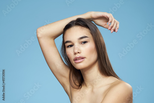 Woman with naked shoulders long hair cosmetics attractive look blue background