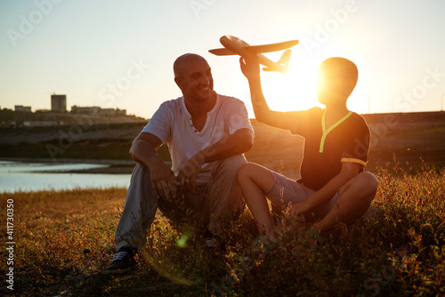 dad and son at sunset in the summer play an airplane in the sun. Family concept