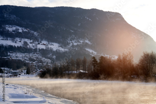 The river is about to freeze. It is very cold and the river is much warmer than the air, therefore the smoke or the damp from the river. Shot at Gol, Norway in February. Minus 20 degreases Celsius. 