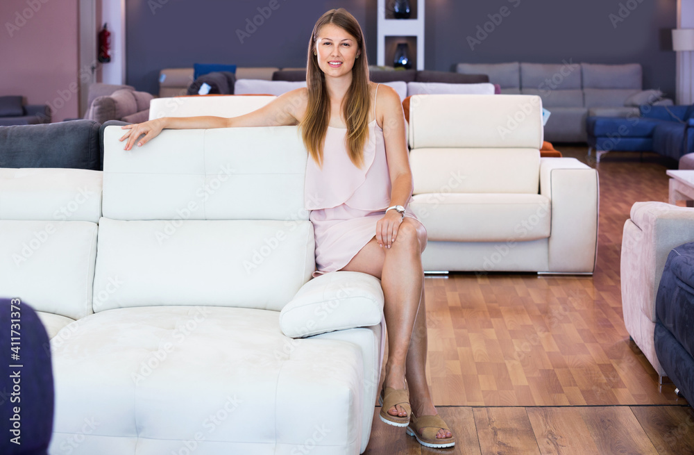 Obraz premium Portrait of happy cheerful smiling woman consumer choosing sofa in furniture shop