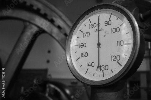 Old tachometer on a very old steam machine. Black and white photo.